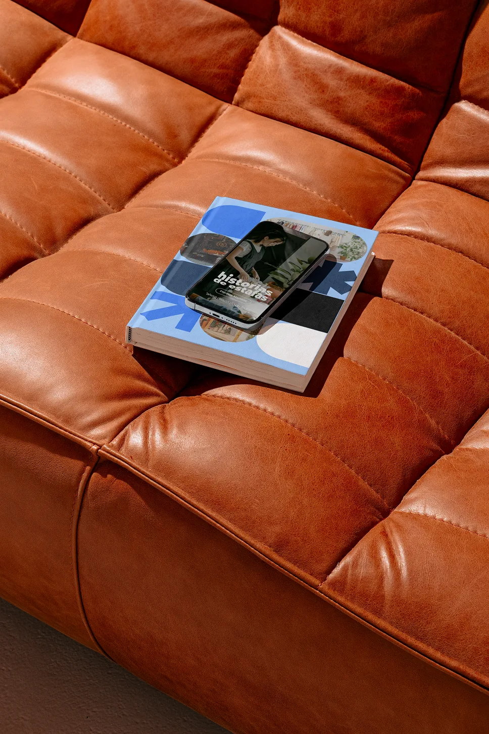 Libro y celular con piezas de identidad visual